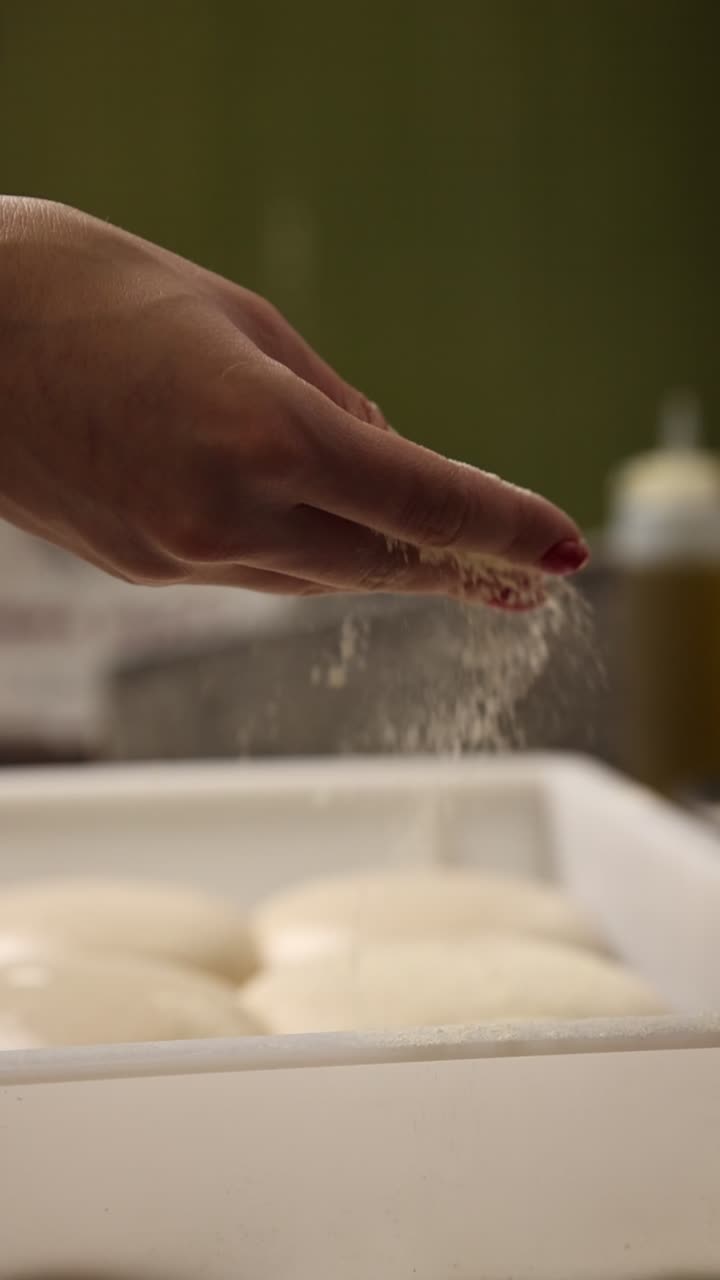 Close-up of Hand Sprinkling Flour Over Pizza Dough Balls