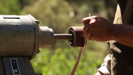 Close-up-of-a-man-using-a-bench-grinder-on-a-sunny-day