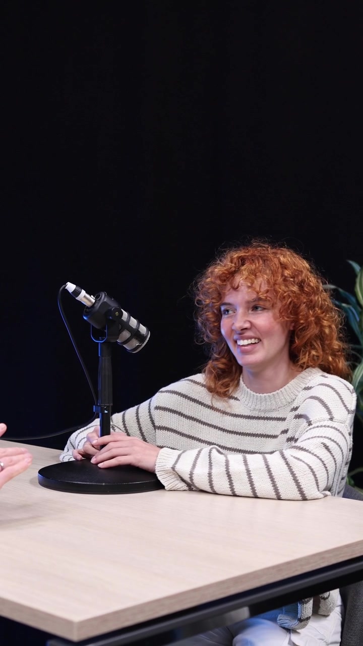 Giovane donna sorridente con capelli rossi ricci che registra un podcast