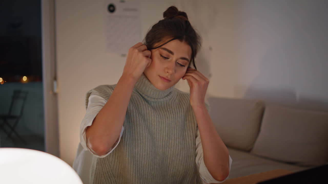 mujer independiente insertando auriculares en el lugar de trabajo nocturno de primer plano. mujer saludando