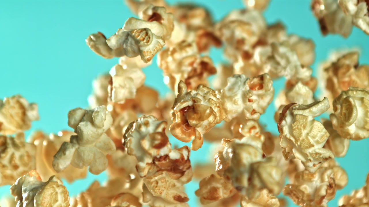 Popcorn dolci al caramello che volano in super slow motion su uno sfondo blu