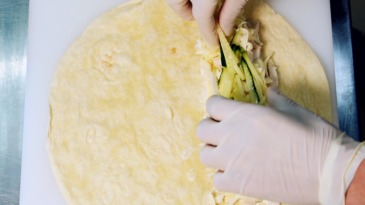 Cooking tasty snack. Professional cook making pita. Adding fresh cutted vegetables on meat pita. Close-up process. Top view
