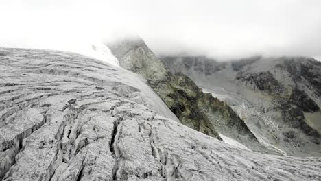 panning aerial view towards the crevasses at the edge of the moiry glacier near grimentz in valais, switzerland with the glacial tongue and lake in the valley in view