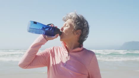 mujer mayor bebiendo agua en la playa