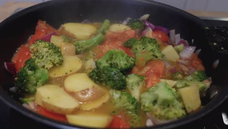 close up of making scrambled eggs with vegetables in a frying pan