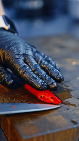 chef cutting red hot chili pepper with a big knife. cook preparing a dish. close up. vertical video.