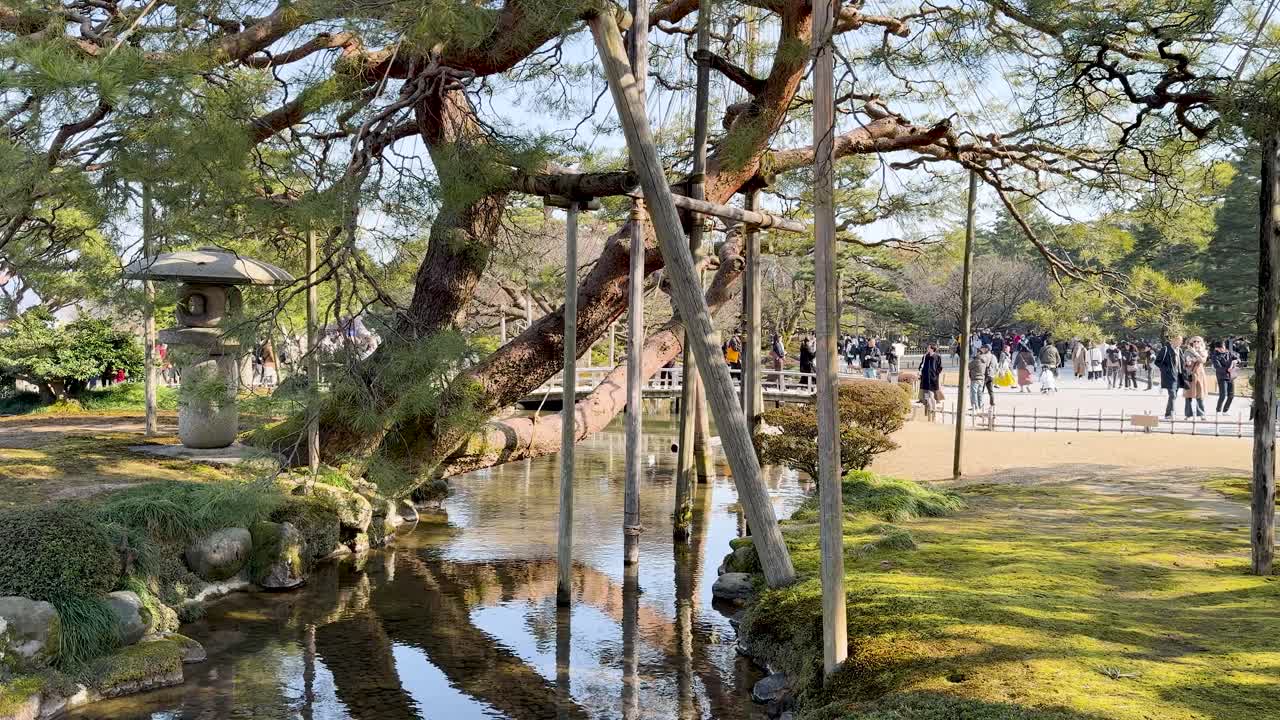 日本の金沢にある歴史的な兼六園の風景を散策する人々の広角静止画