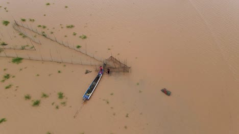 pescadores fijando trampas de red de pesca con punta de flecha a lo largo de las vías fluviales inundadas de barro marrón del delta del mekong