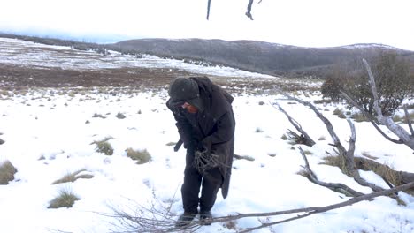 a traditional bushman preparing fire wood out in the snowy mountains