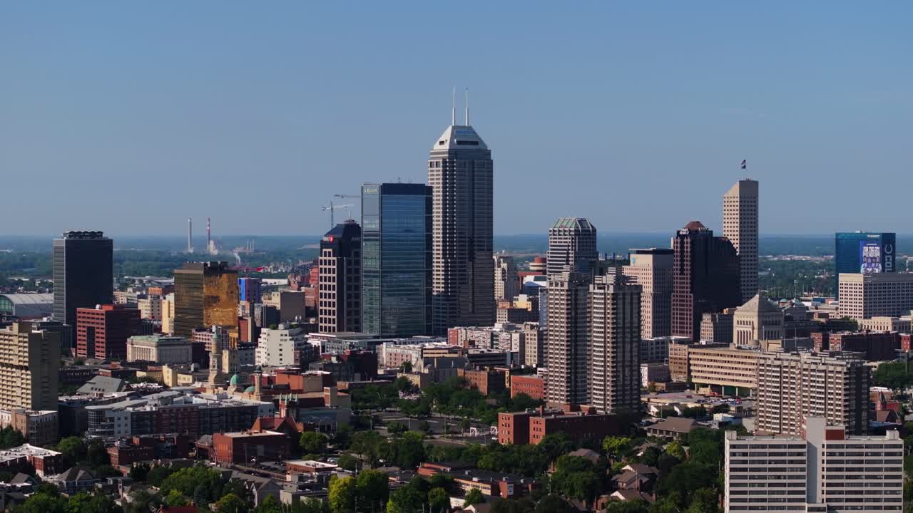 Drone pans up over green park to reveal downtown Indianapolis skyline on sunny summer day