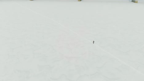person silhouette crosses white frozen river against bridge