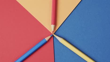 overhead view of crayons on colourful background, in slow motion