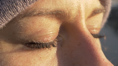 macro primer plano de una mujer relajada cerrando los ojos en cámara lenta con iluminación dorada de puesta de sol