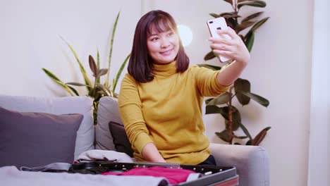 Asian-woman-taking-selfie-while-preparing-for-travel