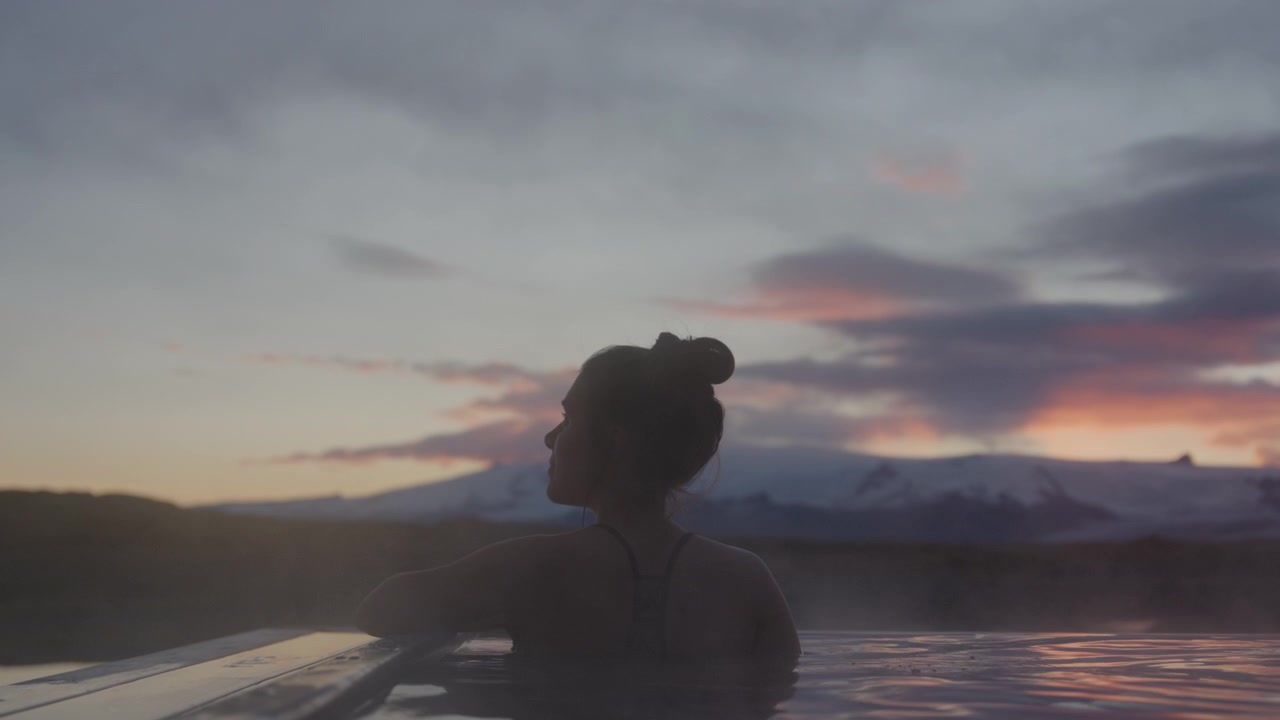 Young woman relaxes, hot spring water, Vatnajökull glacier background