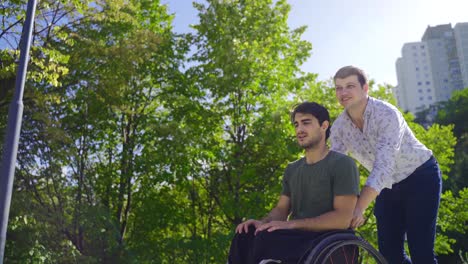 the man drives the wheelchair of the disabled teenager.