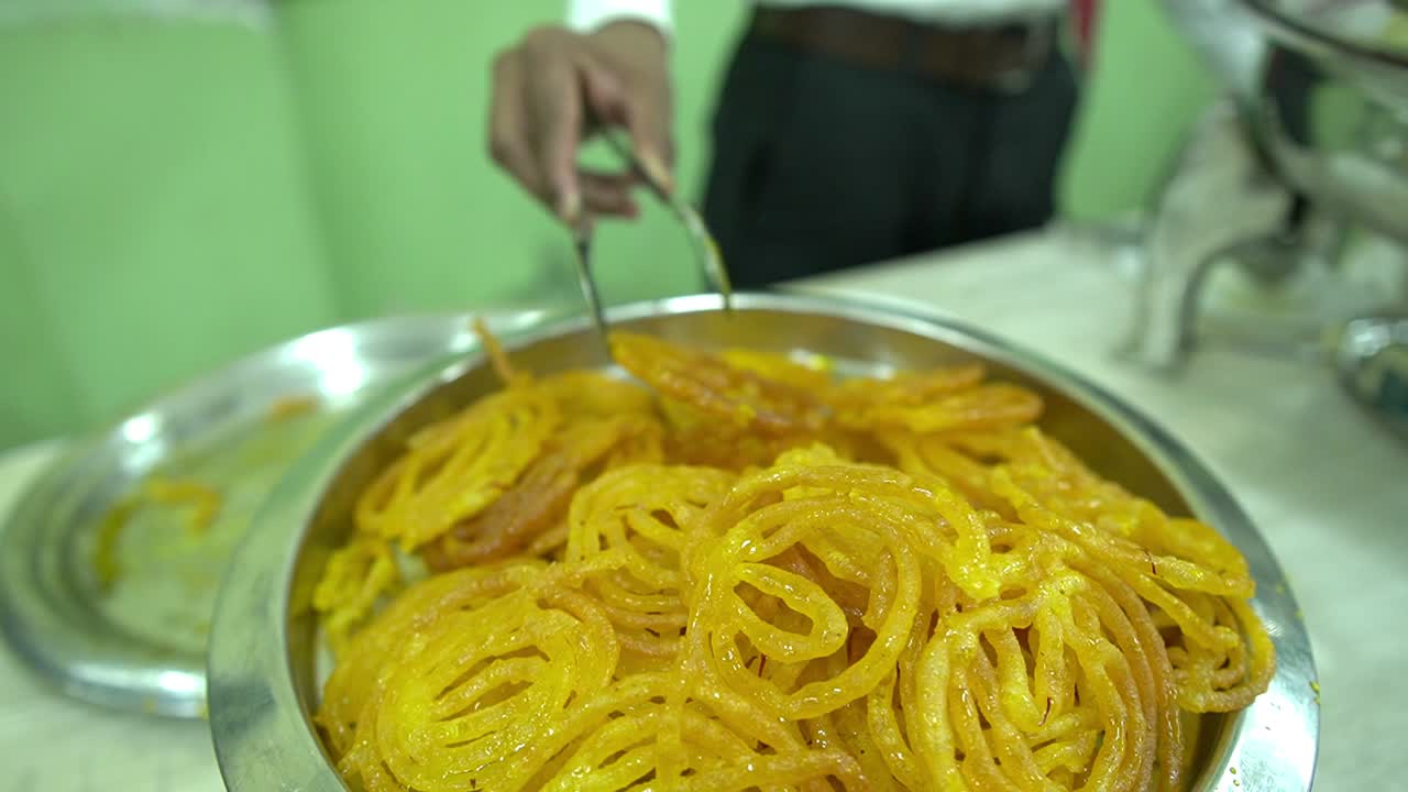 Slow motion cinematic shot of jalebi serving by a chef in white shirt