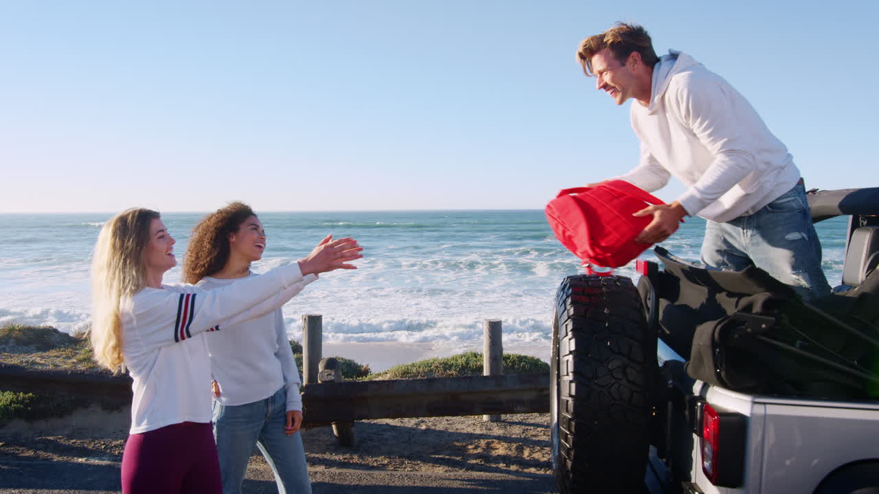 cuatro amigos descargando mochilas de la parte trasera de su coche