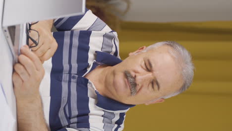 vertical video of home office worker old man looking at camera depressed.