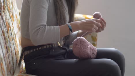 Vista-Lateral-Media-De-Una-Mujer-Envolviendo-Una-Bola-De-Hilo-De-Un-Carrete-Rosa-Más-Grande