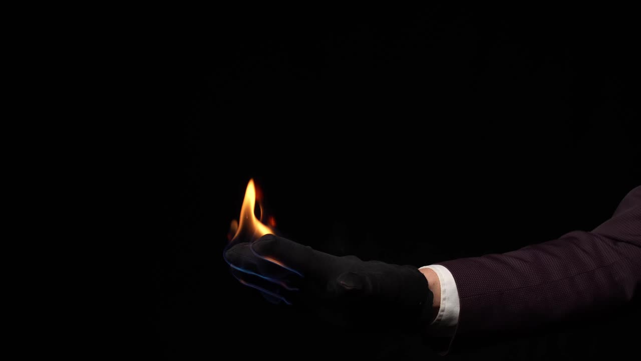 Magician's gloved hand holding a mystical glowing flame, performing a powerful magic trick, symbolizing illusion, power, and sorcery against a dark background, creating mystery