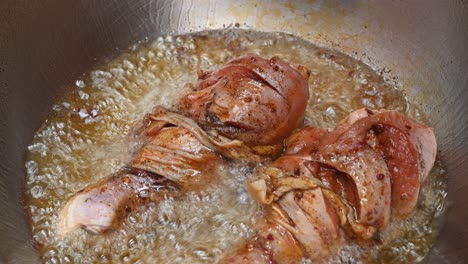 two pieces of chicken drumstick sizzling in a hot deep oil in a frying pan