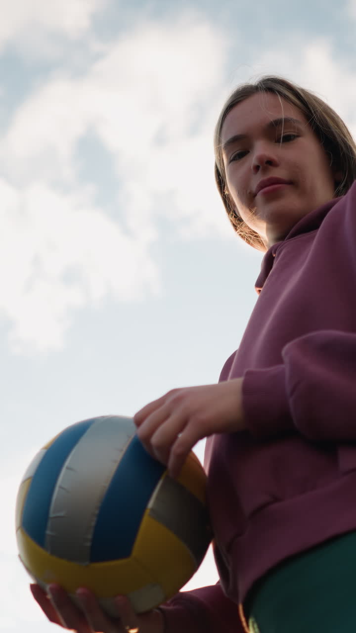 배구 연습 도중 놀이를 준비하는 운동 선수가 뜨거운 빛으로 카메라를 바라보며 발 주위에 황금빛을 만들고 있습니다.