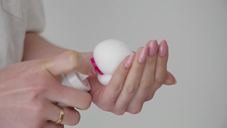 close up of woman's hands squeezing egg mousse cream facial mask on palm