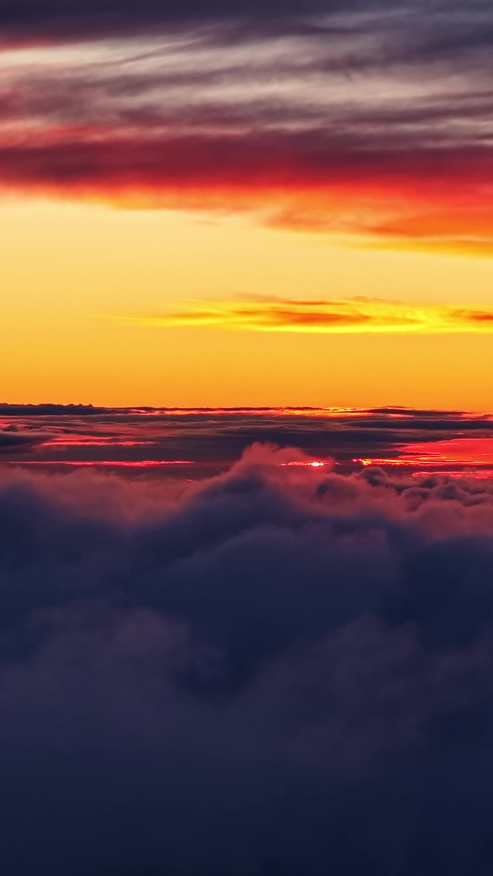 Lebhafter Sonnenuntergangshimmel mit roten und orangefarbenen Farbtönen über Wolken, vertikale Aufnahme