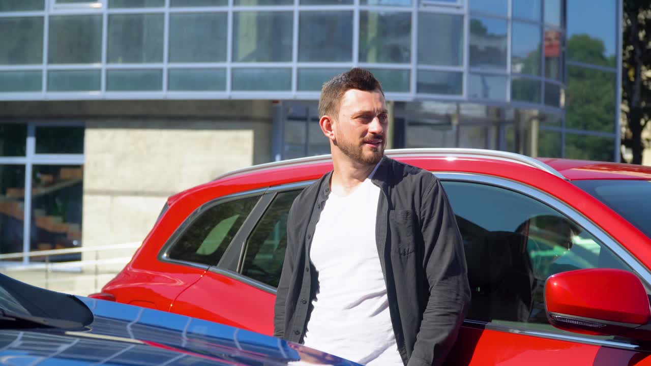 exitoso sonriente confiado joven empresario mirando a la cámara cerca de coche de lujo en un gran centro de negocios