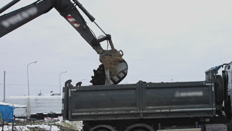 excavator loading dirt onto dump truck in winter construction site