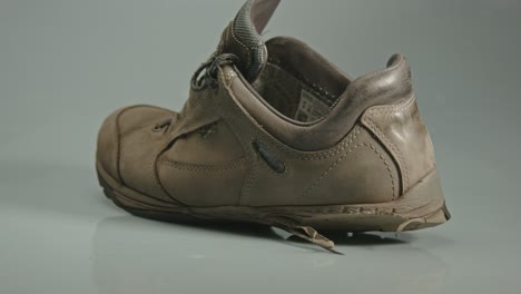 dolly in of worn and damaged hiking shoes in a studio background