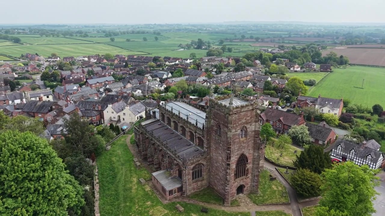 La splendida Chiesa di St Oswald e la circostante Malpas - rotazione del drone da vicino, che rivela il villaggio, Cheshire, Regno Unito.