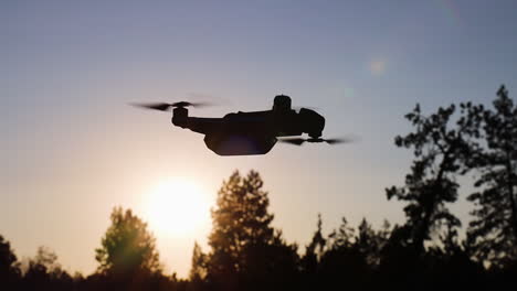 silhouette of a drone hovering at sunset in slow motion