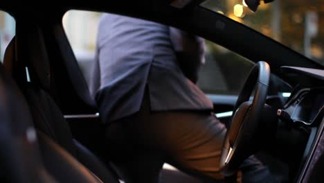 businessman getting in the car at charging station 4k