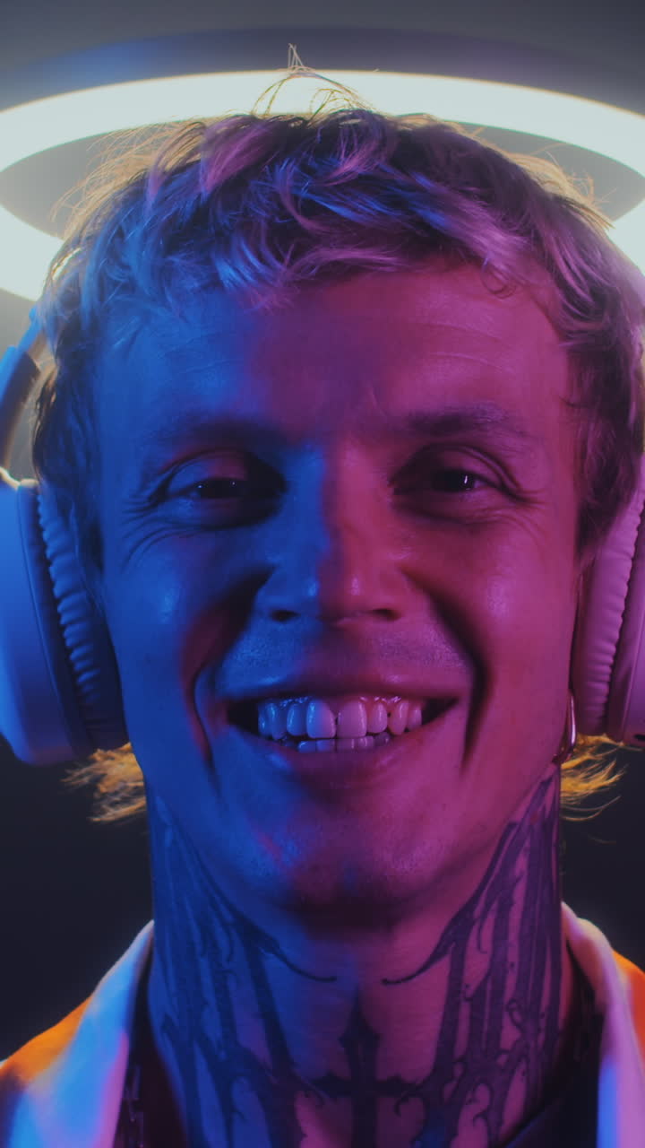 Portrait of Caucasian Man in Headphones under Ring Light in Neon Room