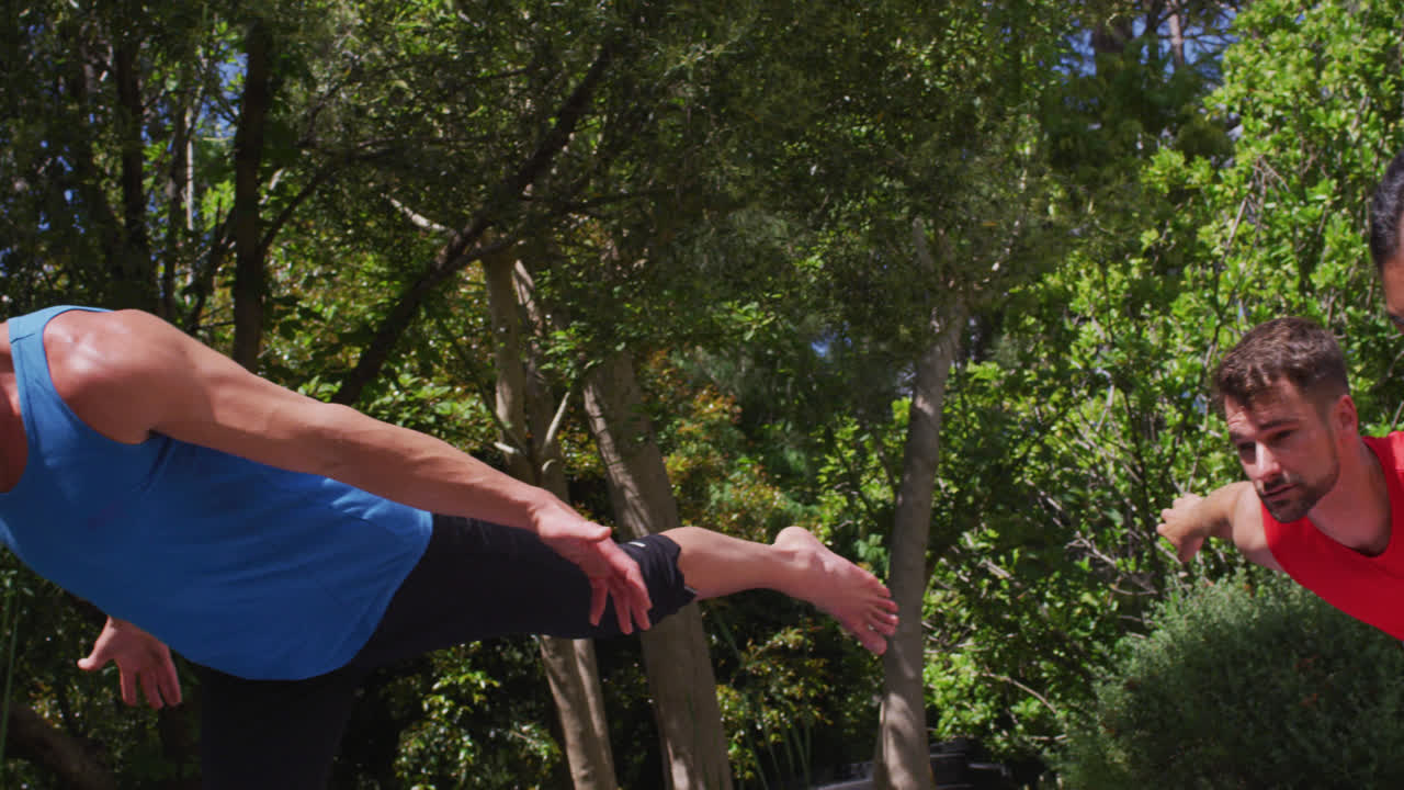instructora de yoga caucásica y grupo diverso practicando la postura de yoga en el parque soleado