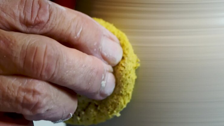 Close up of the potter's hand shaping and molding clay on a turning wheel