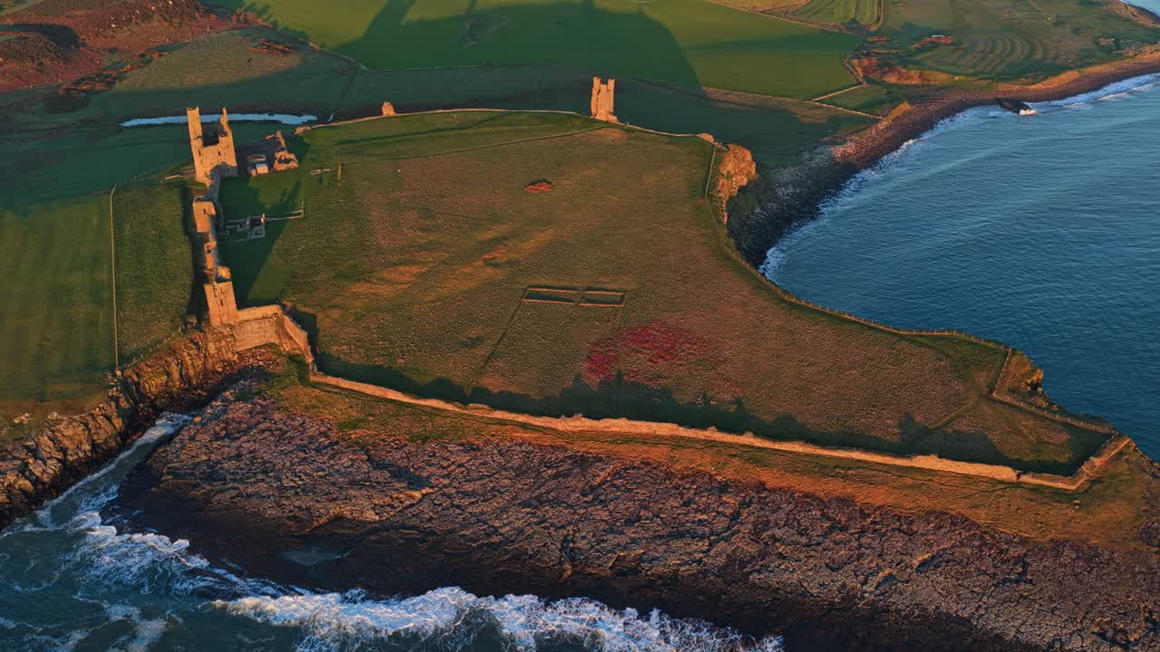 Dunstanburgh slotsruiner på Northumberlandkysten ved solopgang