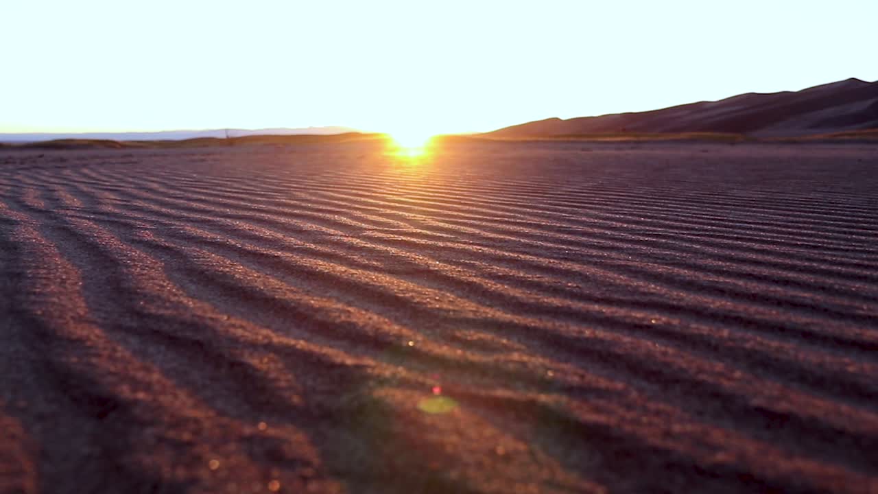 Low ground shot of a sunset on the horizon of an empty sand dune in a desert