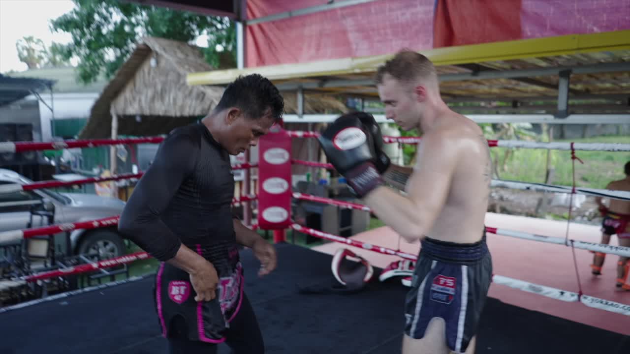 Men training Muay Thai and sparring in a boxing ring