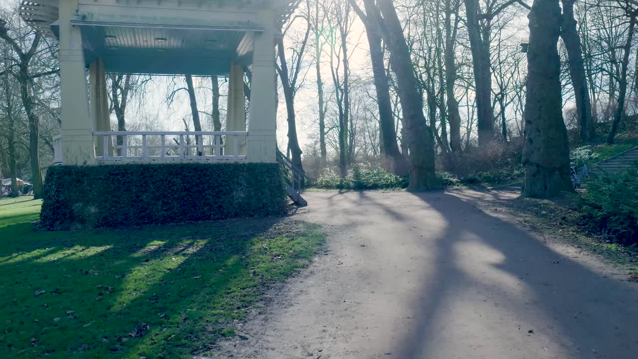Pavillon in einem sonnigen Park mit langen Baumschatten