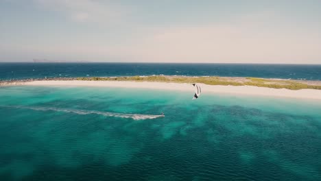 man doing speed kiteboard along caribbean white sand beach, aerial view los roques