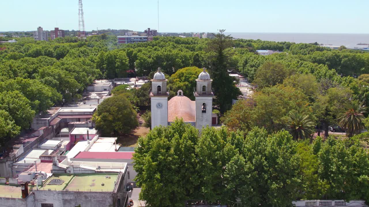 órbita aérea de una iglesia antigua escondida entre árboles en un día soleado
