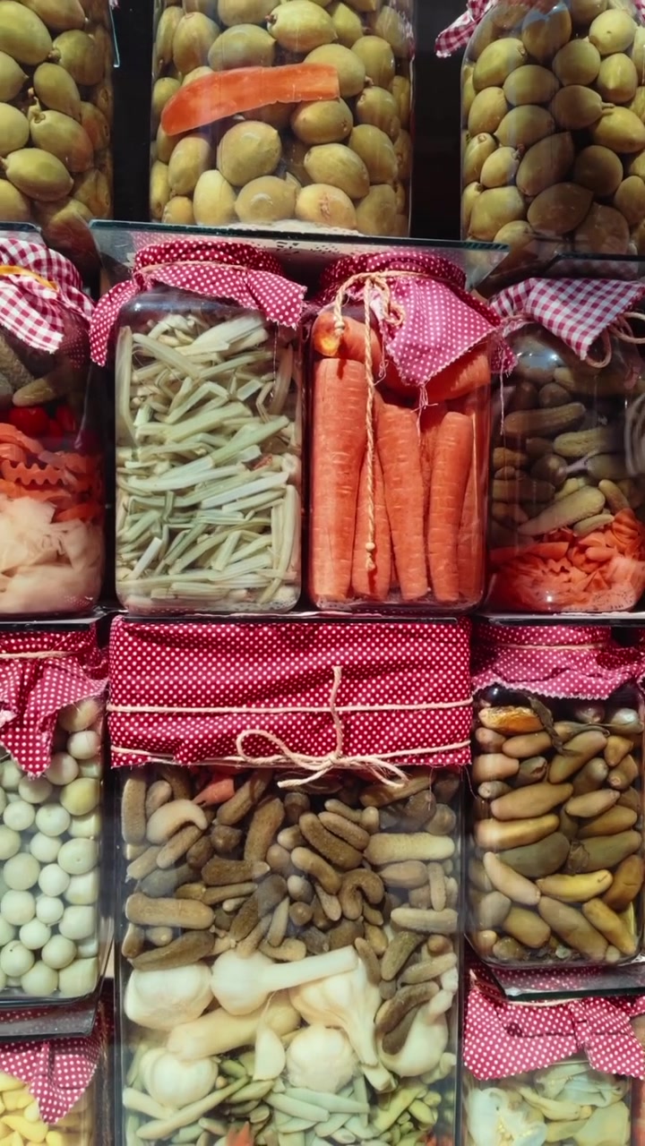 Verdure sottaceto assortite in barattoli di vetro su uno scaffale del mercato