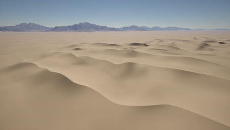 vista aérea de dunas de arena en un desierto con una cordillera en la distancia
