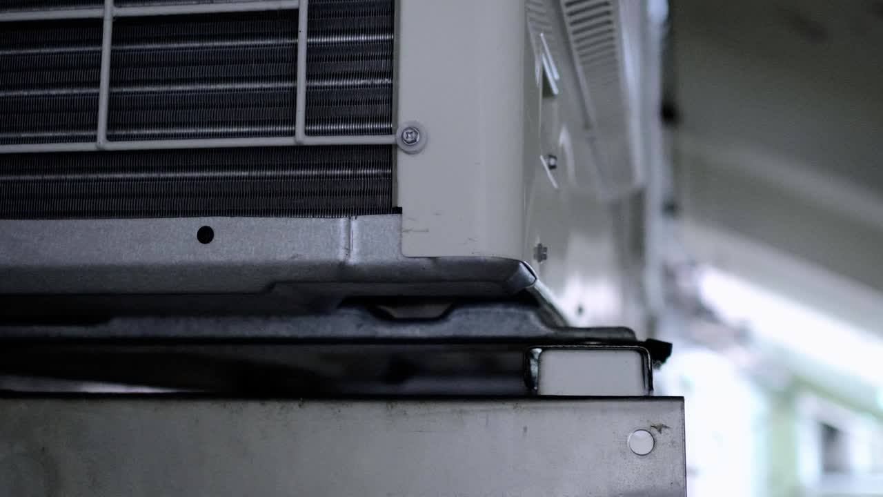 Large air-conditioning compressor is hung on the wall. The subject is on the left.