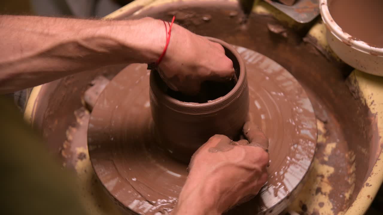 Primo piano di mani maschili che creano una ciotola di argilla su un tornio da vasaio. Artigianato e produzione di esclusive stoviglie da tè in argilla