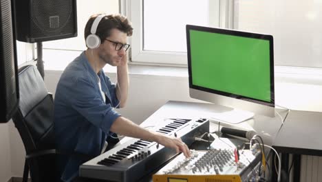 young man in sound recording studio. sit alone and using music mixing console with computer. digital green screen. recording sound in room.