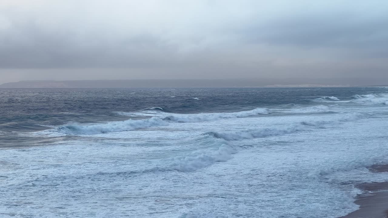 석양 아래 해변 풍경이에요. 멋진 하늘 아래로 강렬한 파도가 몰아치고 있어요.